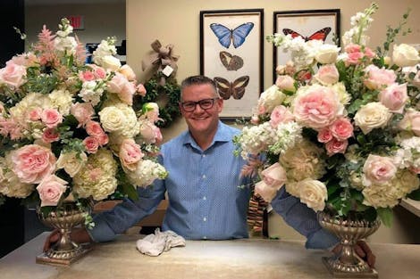 Chad Leitschuh, our Willow Lake store Manager, poses with a pair of large pink floral arrangements