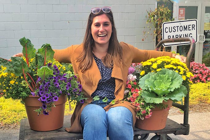  Erin Davidson, our Marketing Coordinator, wraps her arms around a pair of potted plants