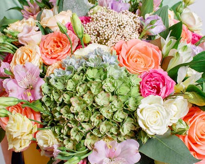A colorful bouquet of orange and pink hydrangea in a large bouquet